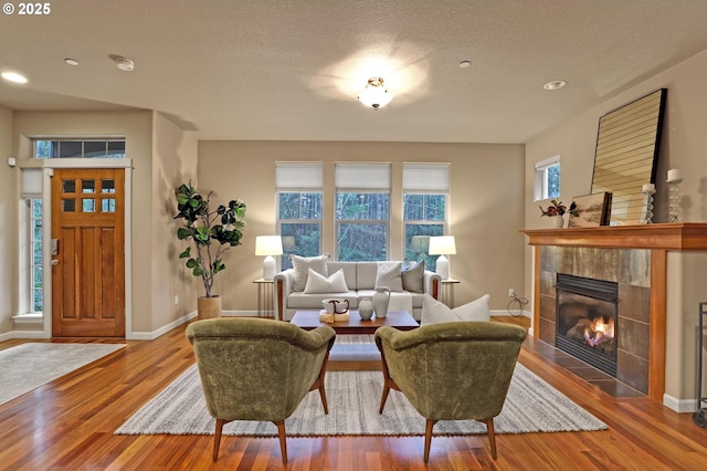 living room featuring hardwood / wood-style flooring, a tiled fireplace, and a textured ceiling