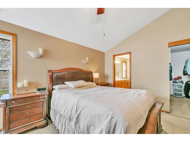 bedroom featuring a closet, light carpet, ensuite bathroom, a walk in closet, and vaulted ceiling