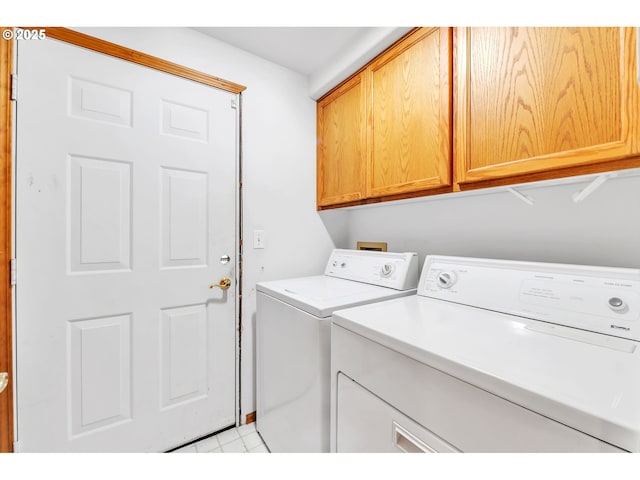 clothes washing area with cabinet space, washing machine and dryer, and light tile patterned flooring