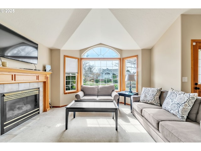 carpeted living area featuring baseboards, vaulted ceiling, and a tiled fireplace