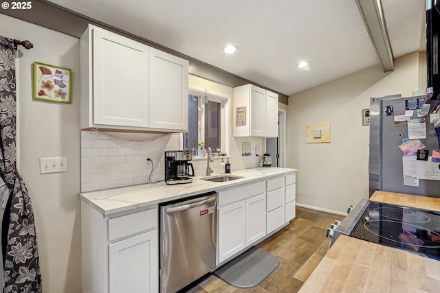 kitchen featuring wood finished floors, a sink, white cabinets, appliances with stainless steel finishes, and decorative backsplash