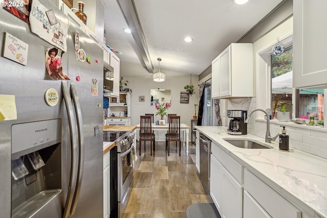 kitchen featuring white cabinets, appliances with stainless steel finishes, backsplash, and a sink