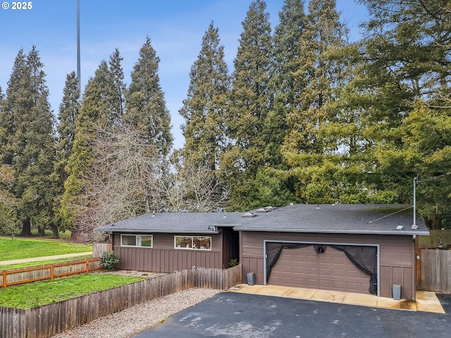 view of front of house with a fenced front yard, a garage, and aphalt driveway