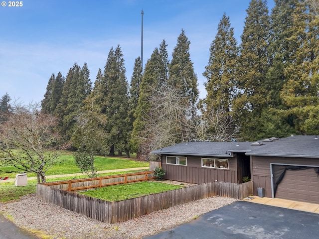 view of front of home featuring a garage, a fenced front yard, a front lawn, and aphalt driveway