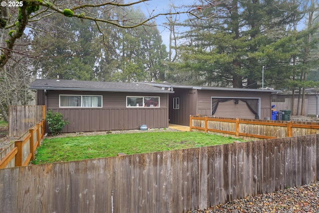 view of front facade with a front yard, fence, and an attached garage