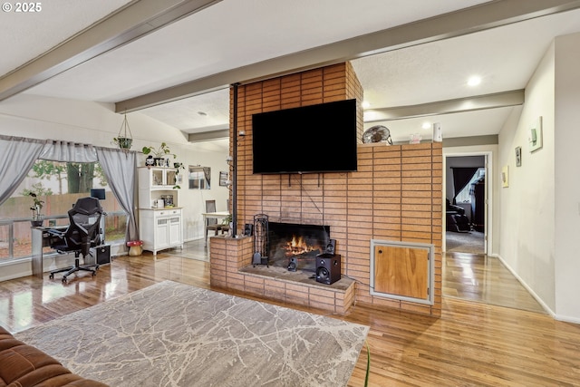 living room with lofted ceiling with beams, a brick fireplace, wood finished floors, and baseboards