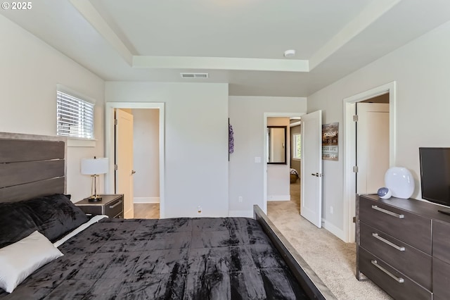 bedroom with multiple windows, visible vents, and a tray ceiling