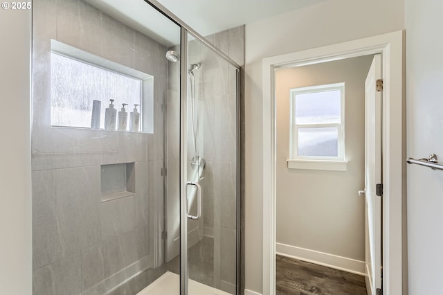 bathroom featuring baseboards, wood finished floors, and a stall shower