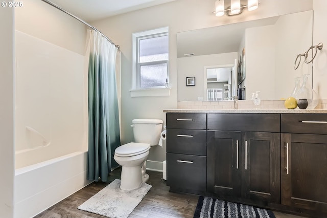 bathroom featuring wood finished floors, vanity, baseboards, toilet, and shower / bath combo with shower curtain