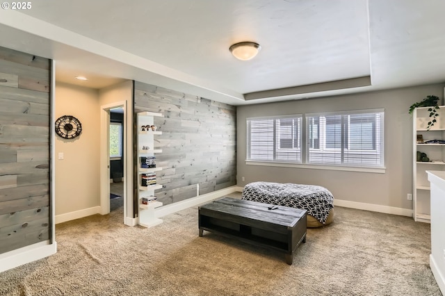 carpeted bedroom with baseboards and a raised ceiling