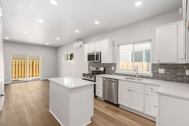 kitchen with stainless steel appliances, light wood-style floors, a wall unit AC, and a sink