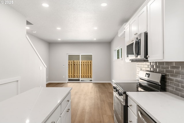 kitchen featuring stainless steel appliances, backsplash, light wood-style flooring, and white cabinets