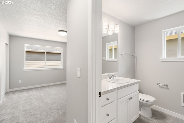 bathroom with toilet, plenty of natural light, a textured ceiling, and vanity