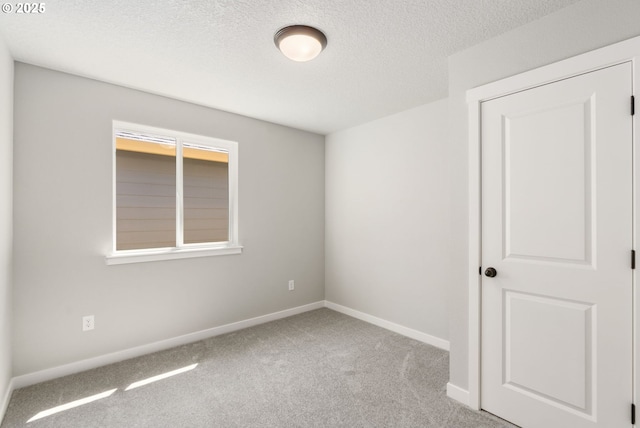 unfurnished room featuring a textured ceiling, baseboards, and carpet flooring