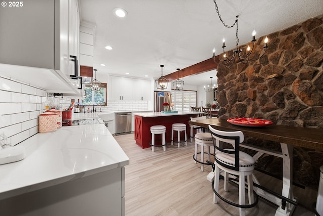 interior space with light wood-style floors, a chandelier, stainless steel appliances, a center island, and backsplash