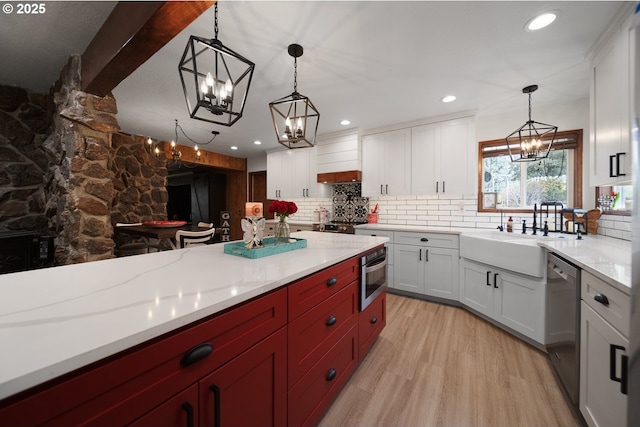 kitchen with a sink, an inviting chandelier, stainless steel appliances, and decorative backsplash