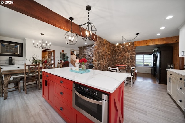 kitchen with white cabinetry, light wood-style flooring, a chandelier, and oven