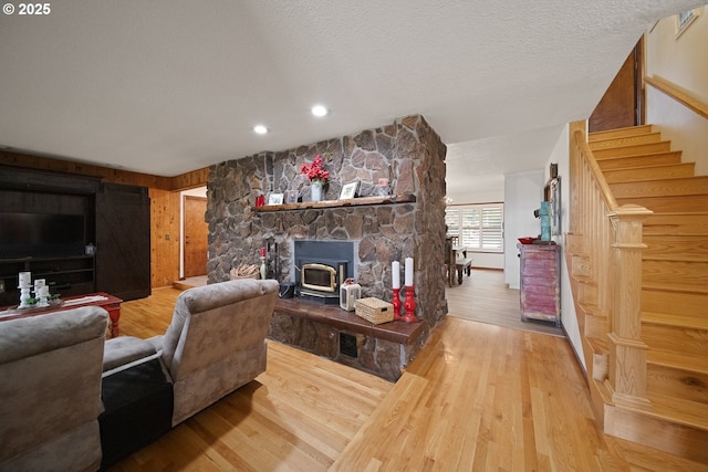 living area with recessed lighting, wood finished floors, baseboards, stairway, and a wood stove