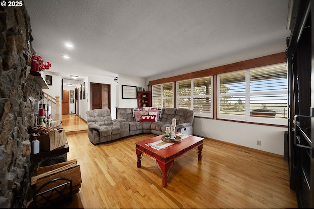 living area featuring a textured ceiling, visible vents, light wood-style flooring, and baseboards