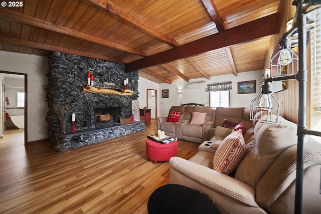 living room featuring a wealth of natural light, wood finished floors, and a stone fireplace