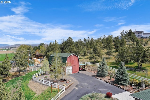 view of barn with fence and aphalt driveway
