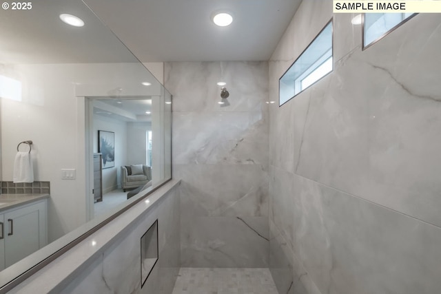 bathroom featuring tiled shower and vanity