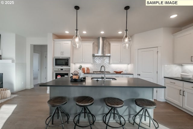 kitchen featuring white cabinets, oven, built in microwave, and wall chimney exhaust hood