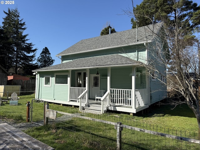 view of front facade featuring covered porch, a shingled roof, fence, and a front yard