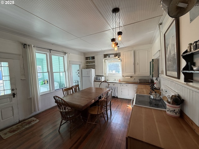 dining area featuring wooden ceiling, dark wood finished floors, and a wainscoted wall