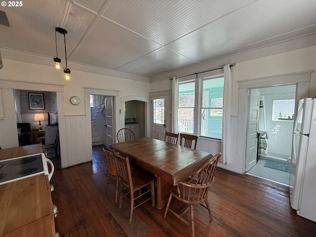 dining room featuring arched walkways, a wainscoted wall, stairs, dark wood finished floors, and washer / dryer