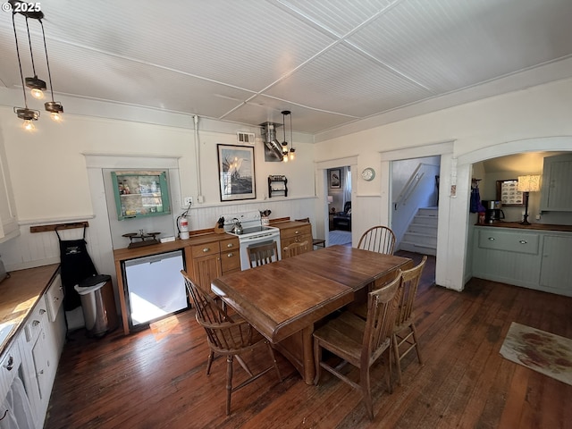 dining area with stairs, dark wood-style flooring, arched walkways, and visible vents