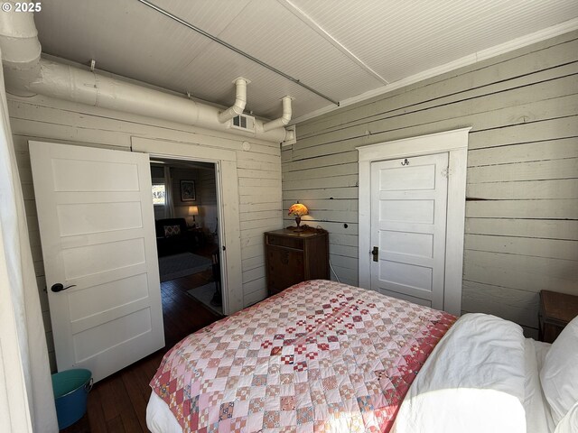 bedroom with wood walls and hardwood / wood-style flooring