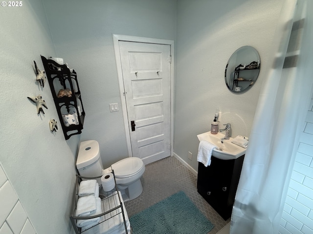 bathroom featuring baseboards, vanity, and toilet