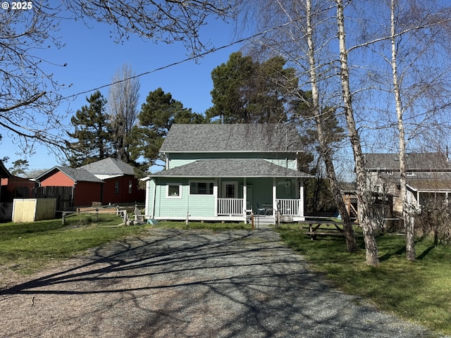 view of front of property with roof with shingles, a porch, fence, driveway, and a front lawn