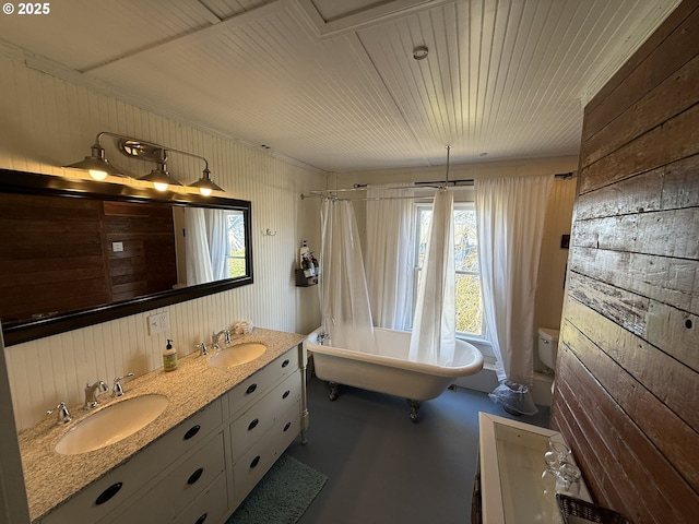 full bathroom with a freestanding bath, wooden walls, and a sink