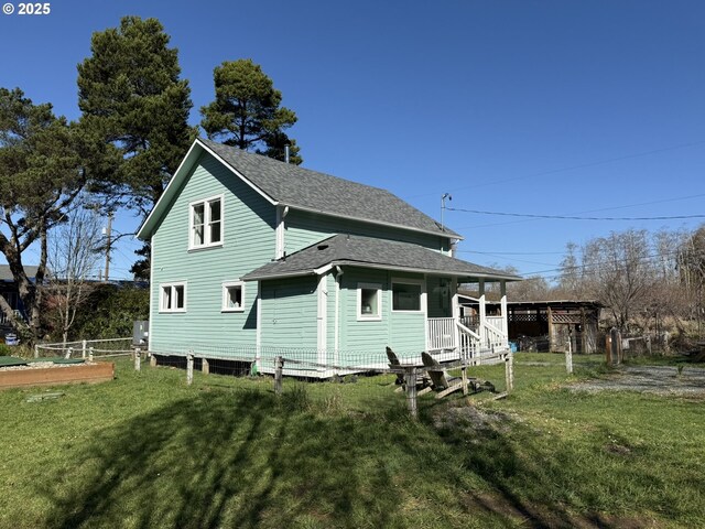 back of house featuring roof with shingles and a yard