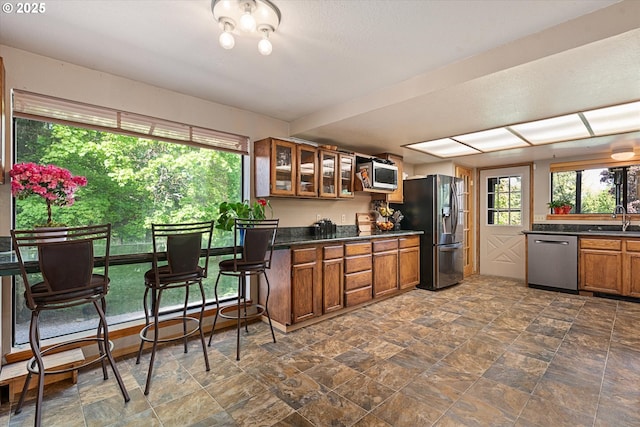 62436 Mink Ln, Summerville, OR 97876 - kitchen with appliances with stainless steel finishes, a sink, brown cabinets, dark countertops, and glass insert cabinets