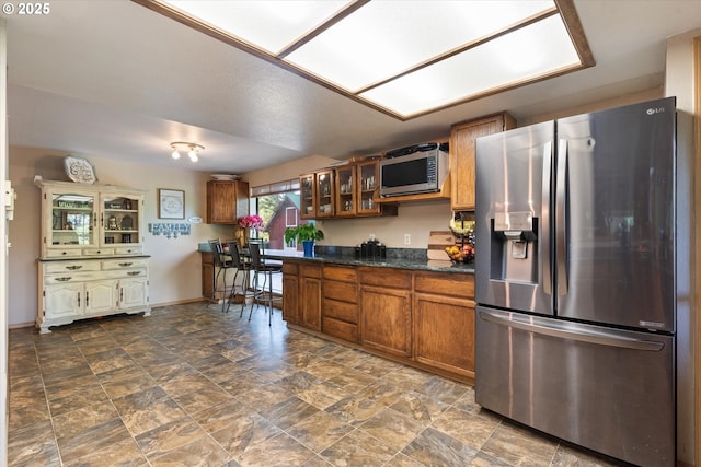 62436 Mink Ln, Summerville, OR 97876 - kitchen with appliances with stainless steel finishes, brown cabinetry, glass insert cabinets, and baseboards