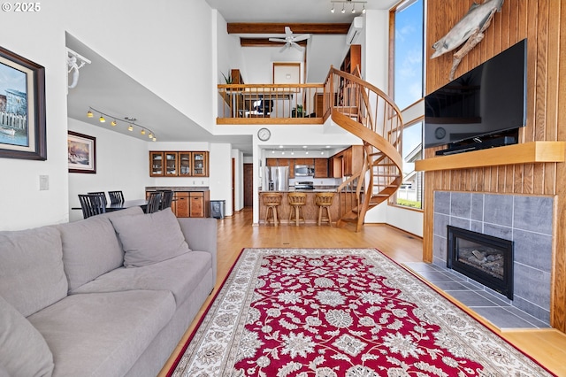 765 5th Ave Unit 5, Hammond, OR 97121 - living room with rail lighting, stairway, a towering ceiling, light wood-style floors, and a tile fireplace