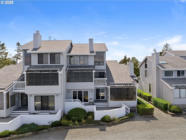 765 5th Ave Unit 5, Hammond, OR 97121 - rear view of property featuring a sunroom, a shingled roof, a balcony, and a chimney
