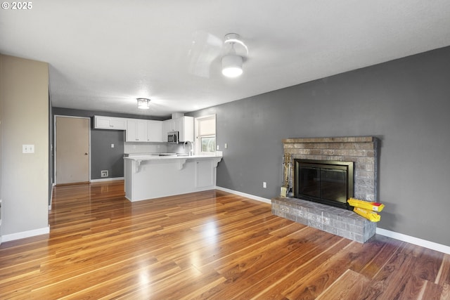 unfurnished living room featuring light wood-type flooring, sink, and a fireplace