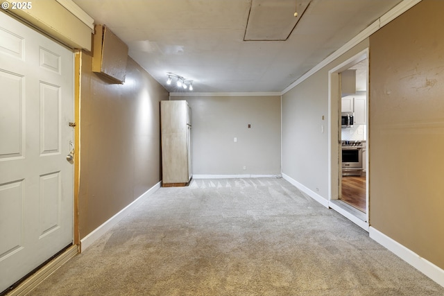 carpeted empty room featuring ornamental molding and track lighting