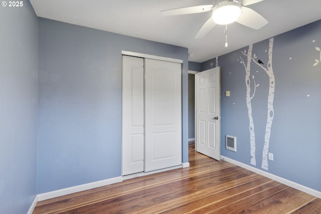 unfurnished bedroom with ceiling fan, dark hardwood / wood-style flooring, and a closet