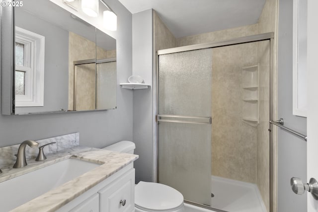 bathroom featuring vanity, a shower with door, and toilet