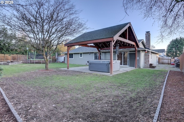 view of yard with a patio area, a gazebo, a hot tub, a trampoline, and a storage unit