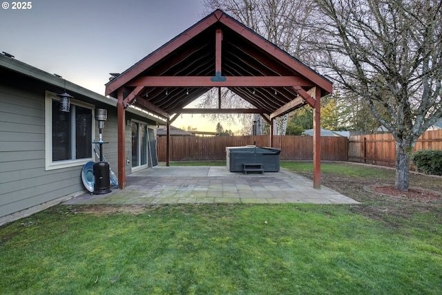 yard at dusk featuring a hot tub, a patio, and a gazebo