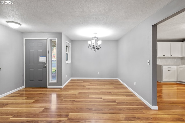 foyer entrance featuring a chandelier, light hardwood / wood-style flooring, and a textured ceiling