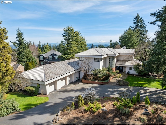 view of front of house featuring stucco siding, a chimney, concrete driveway, and a garage