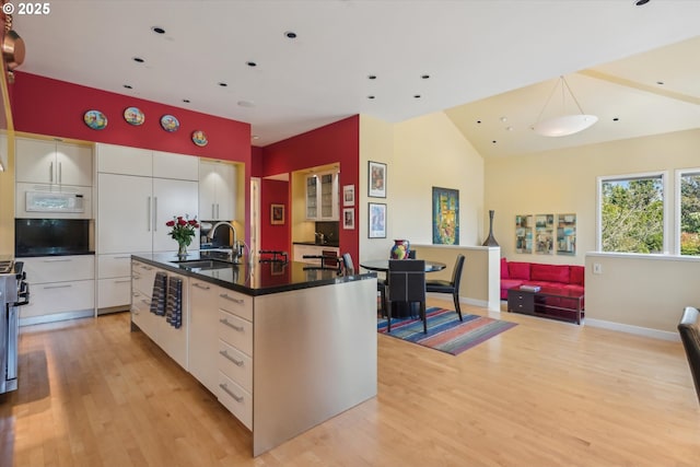 kitchen with dark countertops, modern cabinets, light wood-type flooring, a sink, and white cabinets