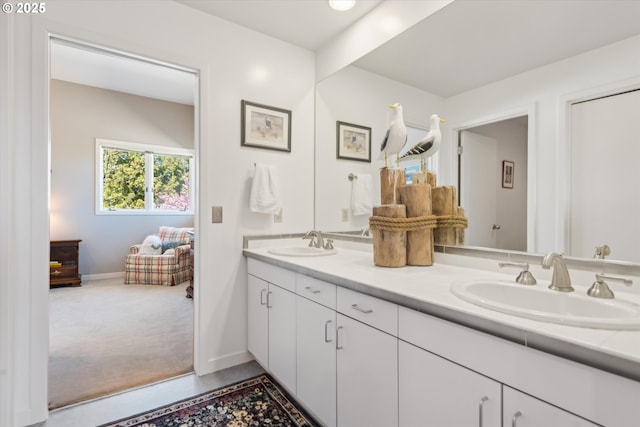 full bathroom featuring a sink, baseboards, and double vanity